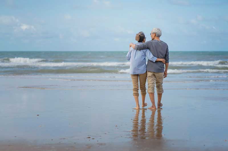 two older adults stand arm in arm
